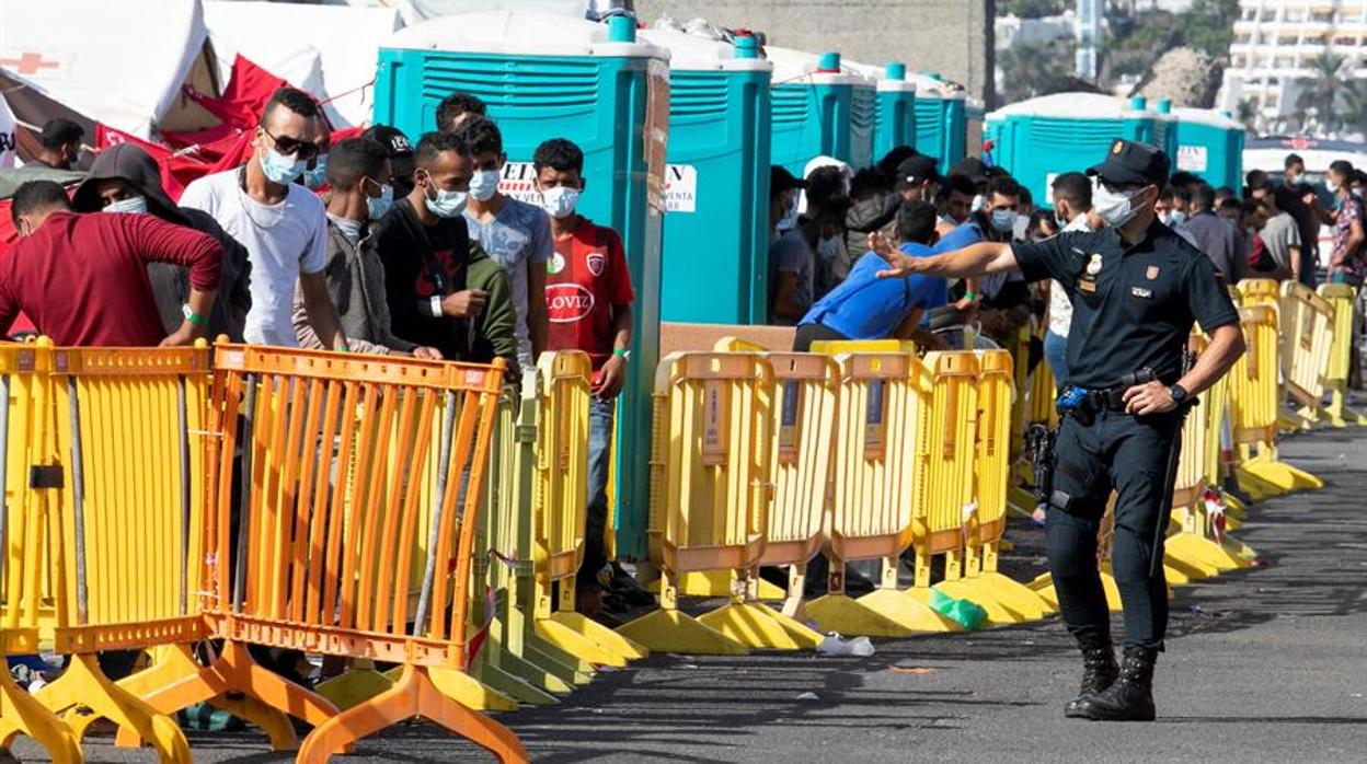 Un agente le da indicaciones a un grupo de inmigrantes en el muelle de Arguineguin