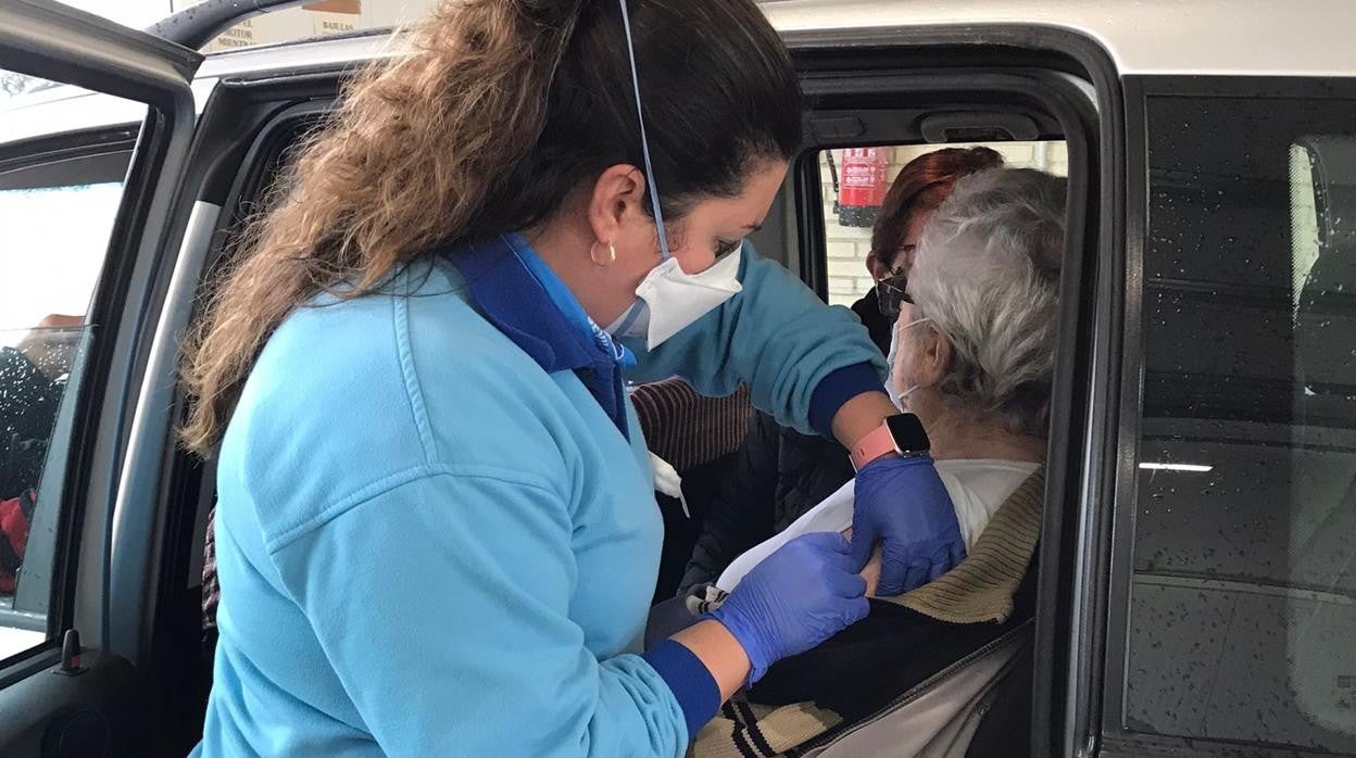 Una enfemera vacuna a una persona mayor en la estación Autocovid del Hospital Millitar