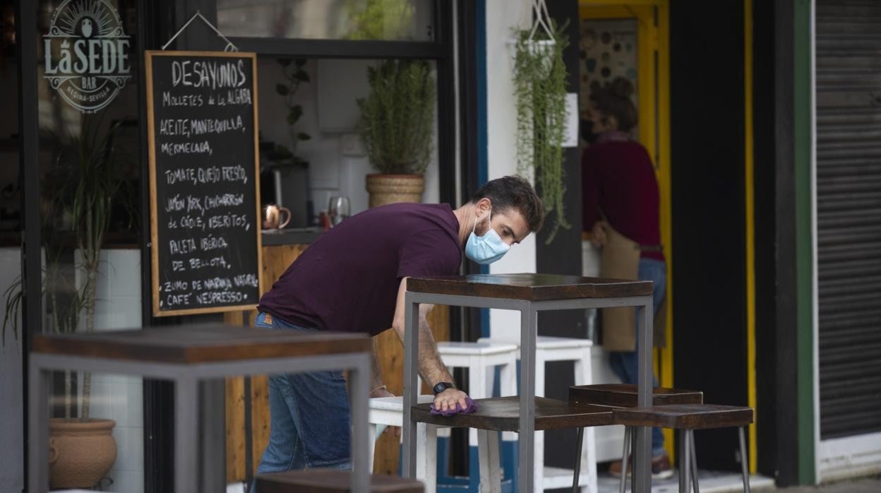 Un camarero prepara veladores en una plaza de Sevilla