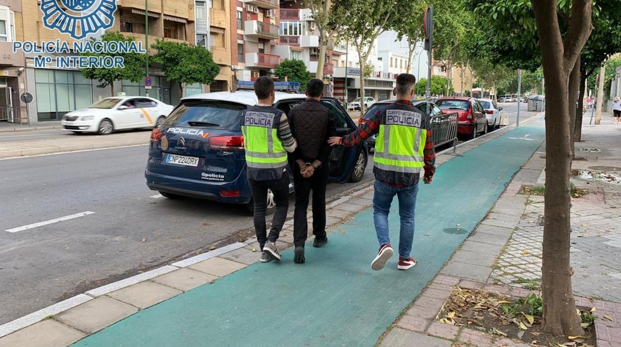 El detenido es trasladado a un vehículo policial por dos agentes