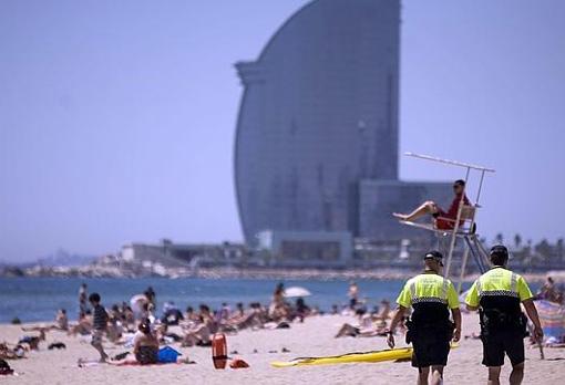 Dos policías pasean por una playa de Barcelona