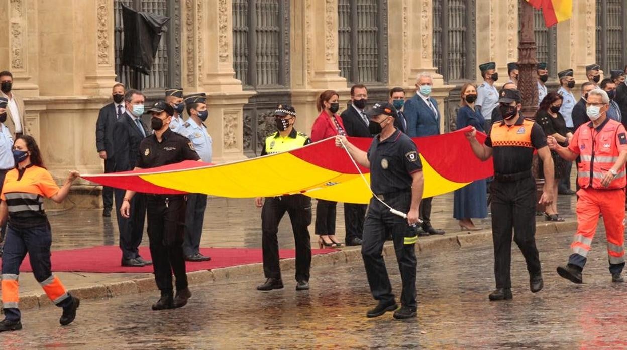 Miembros de los cuerpos de seguridad y servicios públicos portan la bandera nacional