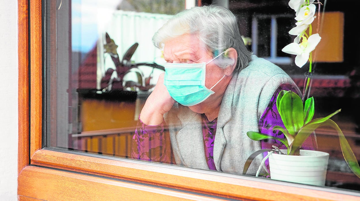 Una mujer asomada a la ventana de su casa en la primera ola de la pandemia