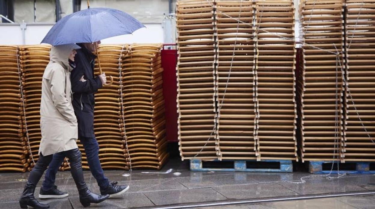 Dos personas pasean al lado de las sillas de la carrera oficial de la Semana Santa de Sevilla