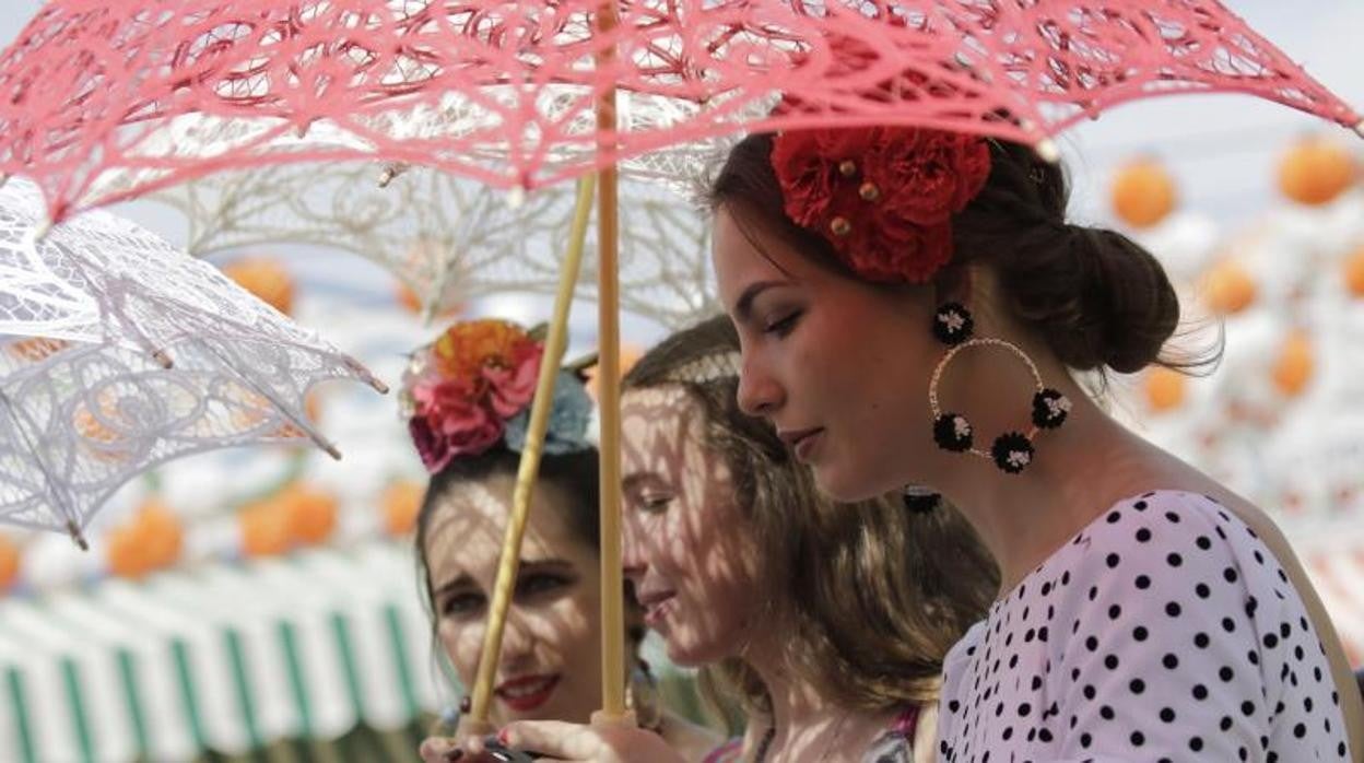 Tres mujeres se protegen del sol en la Feria de Abril de Sevilla