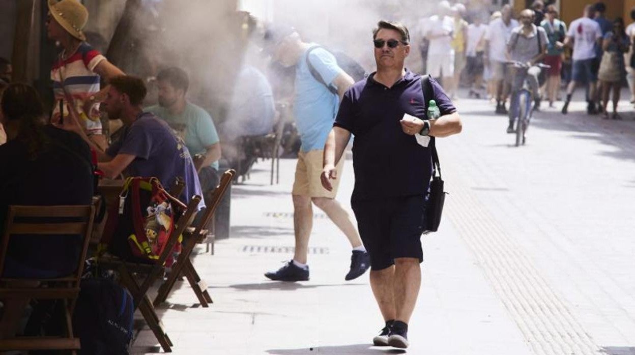 Un señor pasa por debajo de unos aspersores instalados en un bar la semana pasada en Sevilla