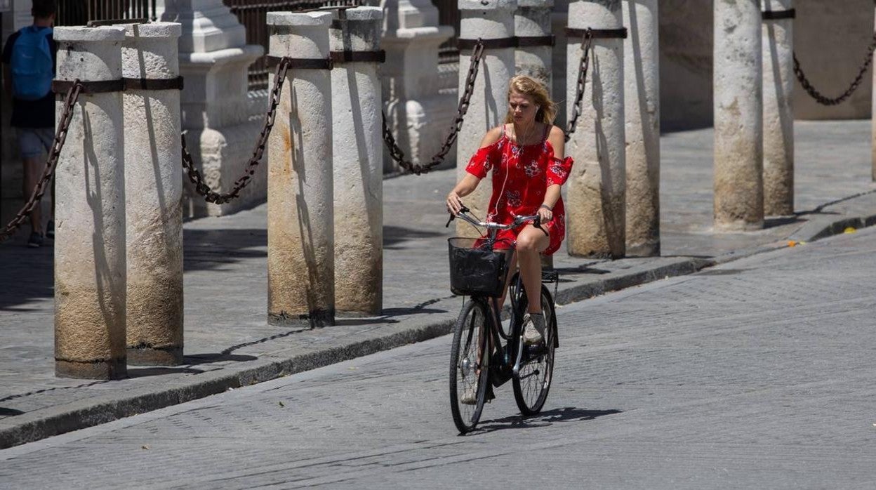 Una turista pasea en bicicleta por el caluroso centro de Sevilla