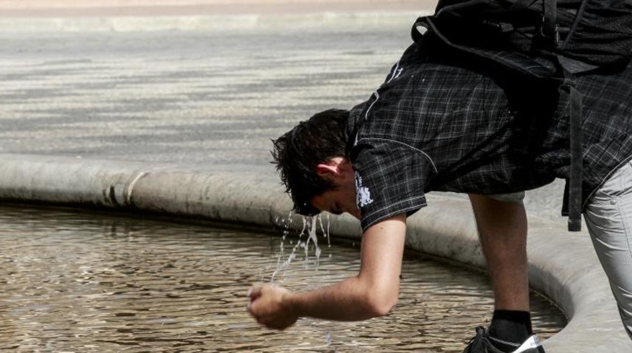 Un hombre se refresca en una fuente de agua en Sevilla