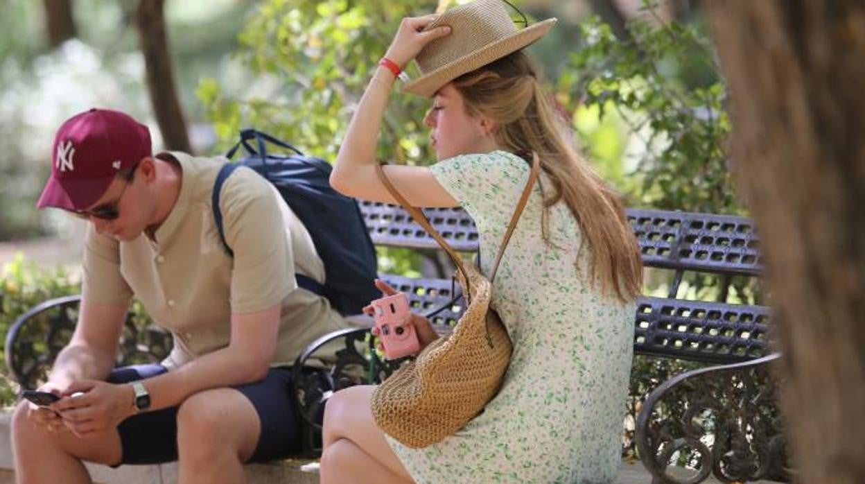 Dos turistas aprovechan la sombra en uno de los días de más calor de junio en Sevilla