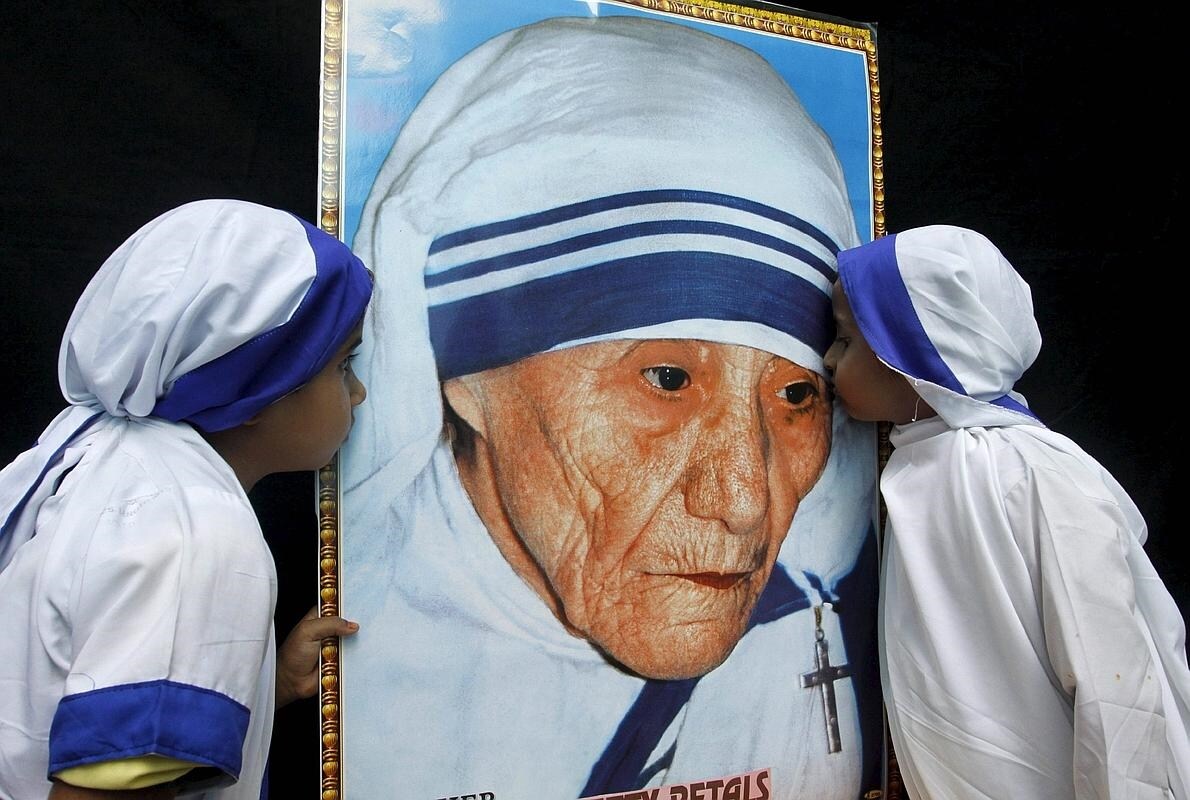 Dos niñas vestidas como Misioneras de la Caridad besna un retrato de la Madre Teresa de Calcuta durante una ceremonia en su honor en Bhopal (India)