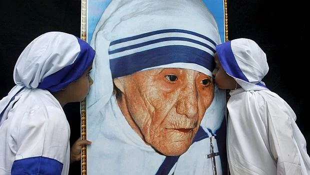 Dos niñas vestidas como Misioneras de la Caridad besna un retrato de la Madre Teresa de Calcuta durante una ceremonia en su honor en Bhopal (India)