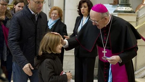 Monseñor Osoro bendice a una niña antes de la celebración de la misa en la catedral de La Almudena