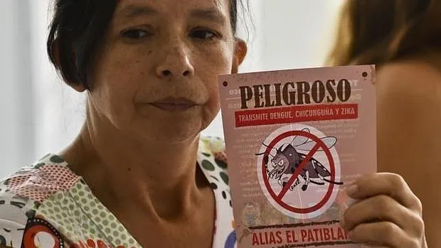 Una mujer sostiene un panfleto que alerta sobre el virus Zika en Colombia
