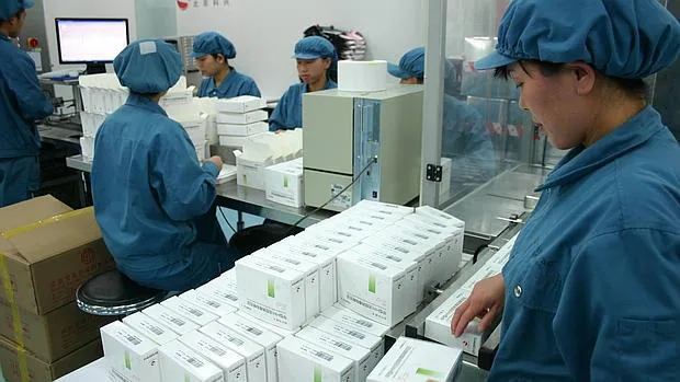 Un grupo de trabajdores chinos revisan la fabricación de vacunas