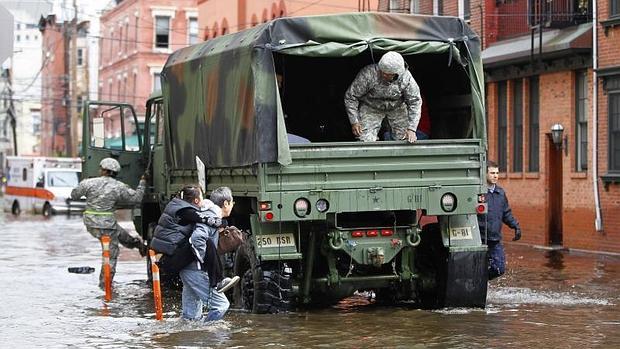 Un hombre lleva a cuestas a su mujer en Hoboken (Nueva Jersey) a un camión de la Guardia Nacional para ser evacuados tras el paso de la tormenta Sandy en 2012