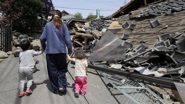Vecinos caminan entre los escombros tras el terremoto de 6,5 en la escala ritcher en la localidad de Mashiki en la prefectura de Kumamoto (Japón)