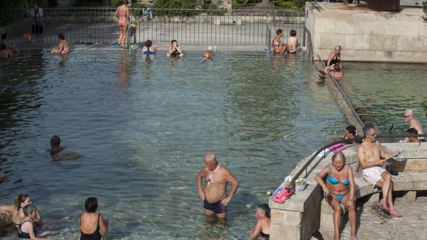 Un grupo de gente disfruta de las altas temperaturas en la zona fluvial del río Miño y las termas de A Chavasqueira, Galicia vive este domingo temperaturas significativamente altas, al igual que ocurre en todo el nordeste peninsular y en la mitad sur, rebasando los 30 grados en varios puntos, sobre todo en Orense