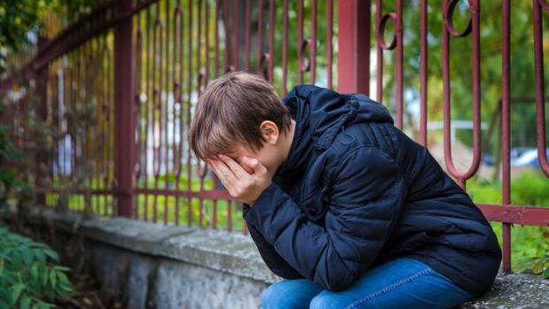 Un niño llora tapándose la cara en la calle