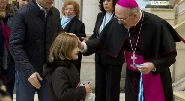 Monseñor Carlos Osoro bendice a una niña en la catedral de La Almudena durante la pasada misa de la familia