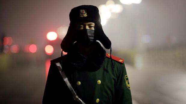 Un policía se cubre el rostro con una mascarilla en plena alerta roja por polución en Pekín