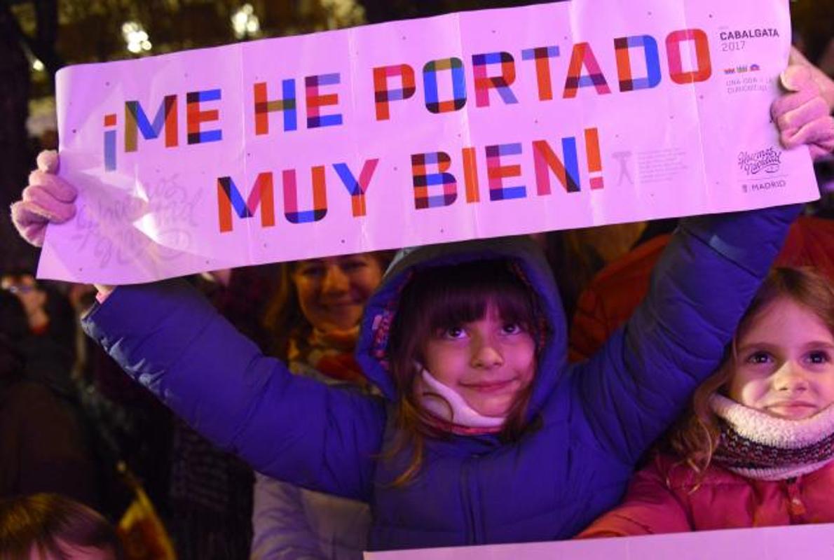 Una niña despliega una pancarta al paso de Sus Majestades de Oriente