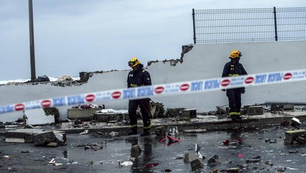 Unos bomberos supervisan el muro caido del paseo marítimo de la playa De Sacaba por el mal temporal, hoy en Málaga