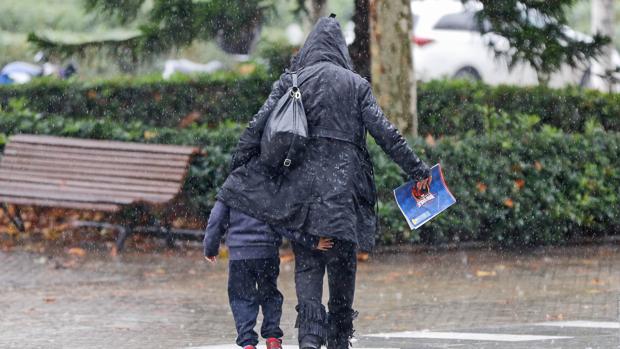 Una madre protege a su hijo de la lluvia y las bajas temperaturas