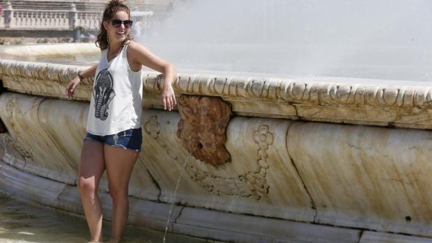 Una chica se refresca en una fuente de la Plaza España en Sevilla