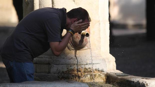 Un hombre se refresca en una fuente de Córdoba durante la ola de calor de junio