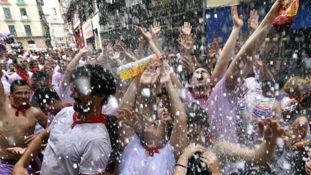 Un grupo de personas abre sus brazos para recibir agua desde un balcón tras el lanzamiento del tradicional chupinazo desde el balcón del Ayuntamiento de Pamplona con el que han dado comienzo las Fiestas de San Fermín 2017