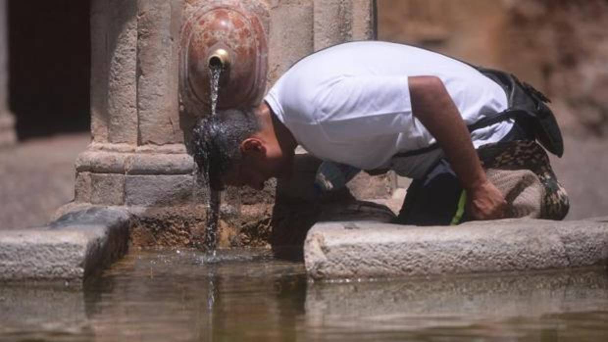 Un hombre se refresca la cabeza en una fuente de Córdoba