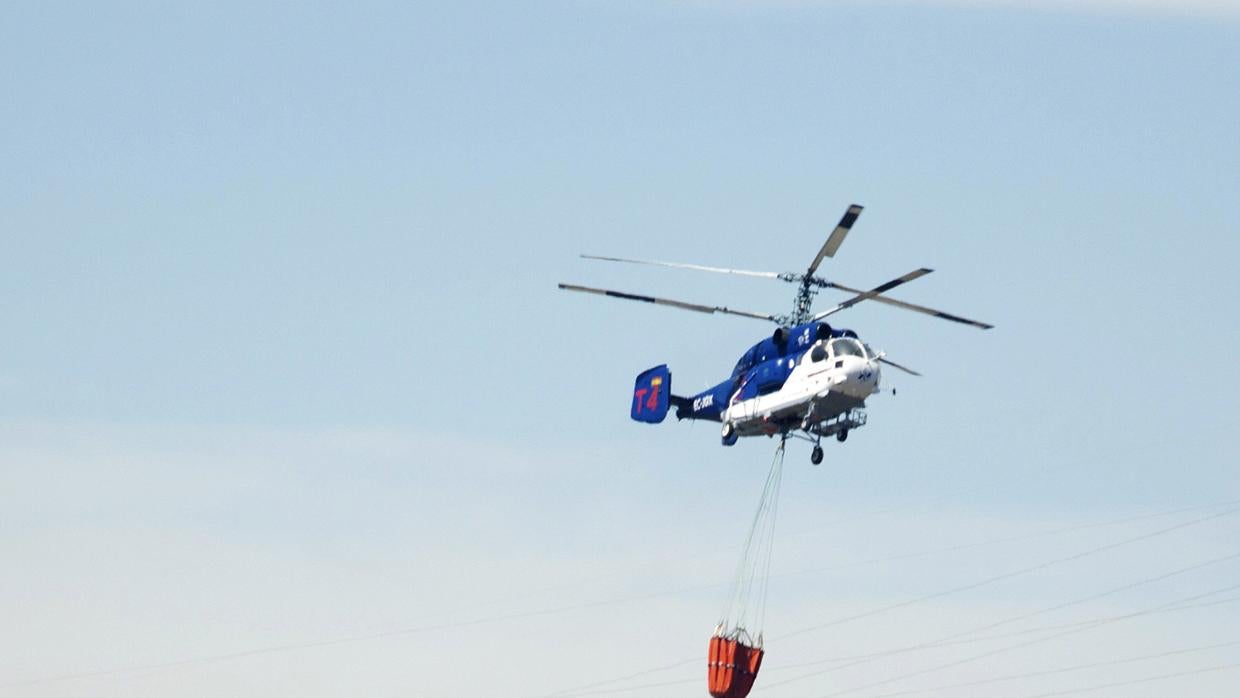 Un helicóptero trabaja para controlar el fuego declarado en Málaga