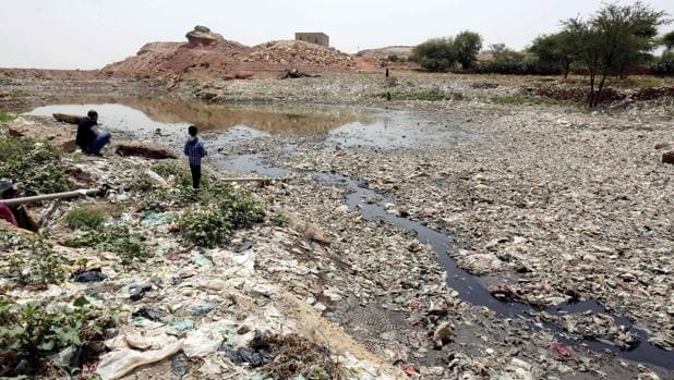 Niños juegan cerca de un pantano de alcantarillado con residuos y desechos que crean un entorno de alto riesgo para el cólera, en Saná (Yemen)