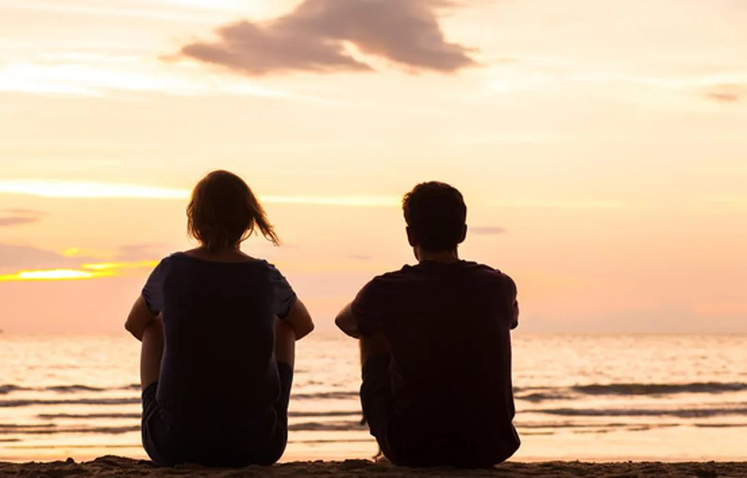 Una pareja mira el atardecer desde una playa
