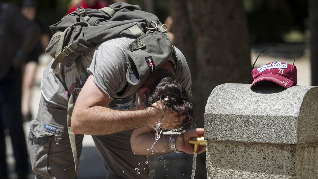 Un hombre se refresca de las altas temperaturas en Madrid