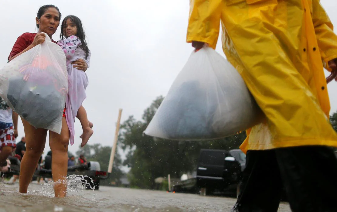 Una mujer y su hija caminan a través de las aguas de la inundación de la tormenta tropical Harvey (Texas)