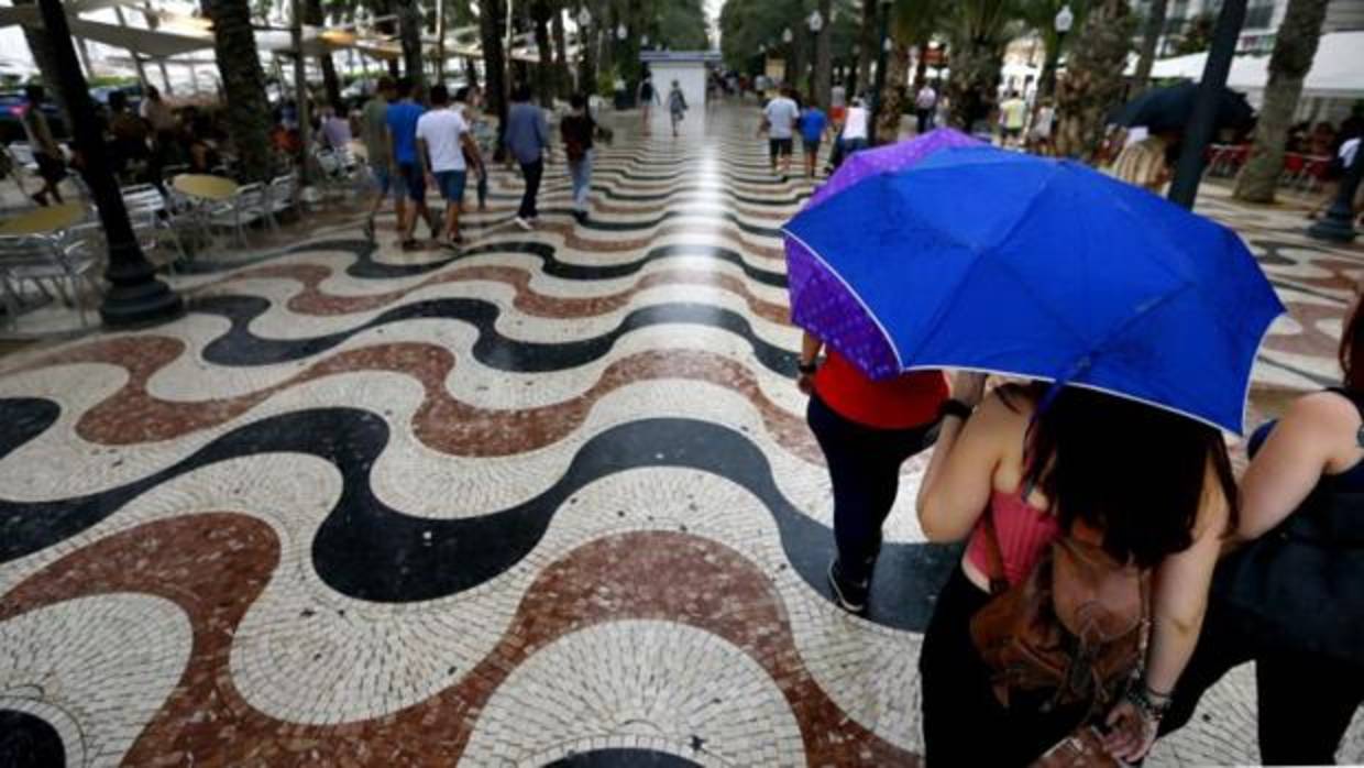 Turistas caminan este martes bajo la lluvia por la Explanada de Alicante