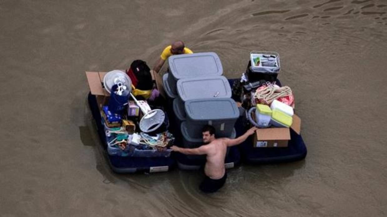 Dos ciudadanos de Houston arrastran sus pertenencias por las calles inundadas