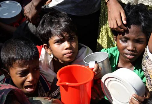SFASDCAMPOS DE REFUGIADOS ROHINGYAS EN BANGLADÉS. 18/11/2017. En cuchillas bajo el sol, con los soldados frenando con varas a la multitud desesperada, los niños esperan al reparto de comida en el campo de refugiados de Moinnnergohna.