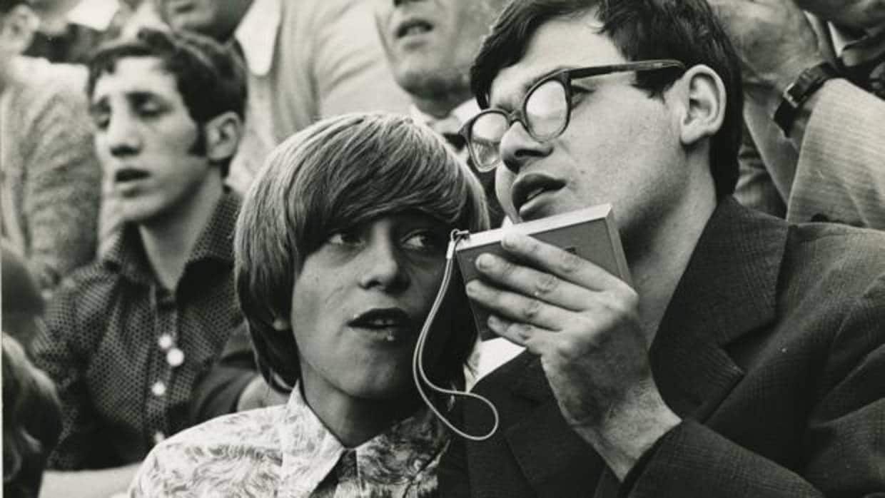 Dos personas usan un transistor para escuchar un partido de fútbol