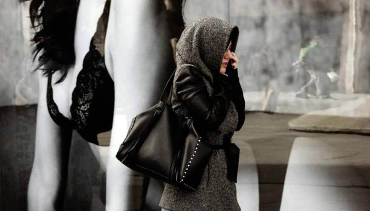 Una mujer se protege del frío en una jornada donde las lluvias han remitido en Pamplona