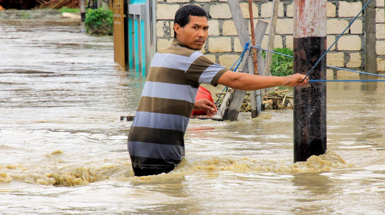 Un residente cruza una calle inundada este lunes en Sentani