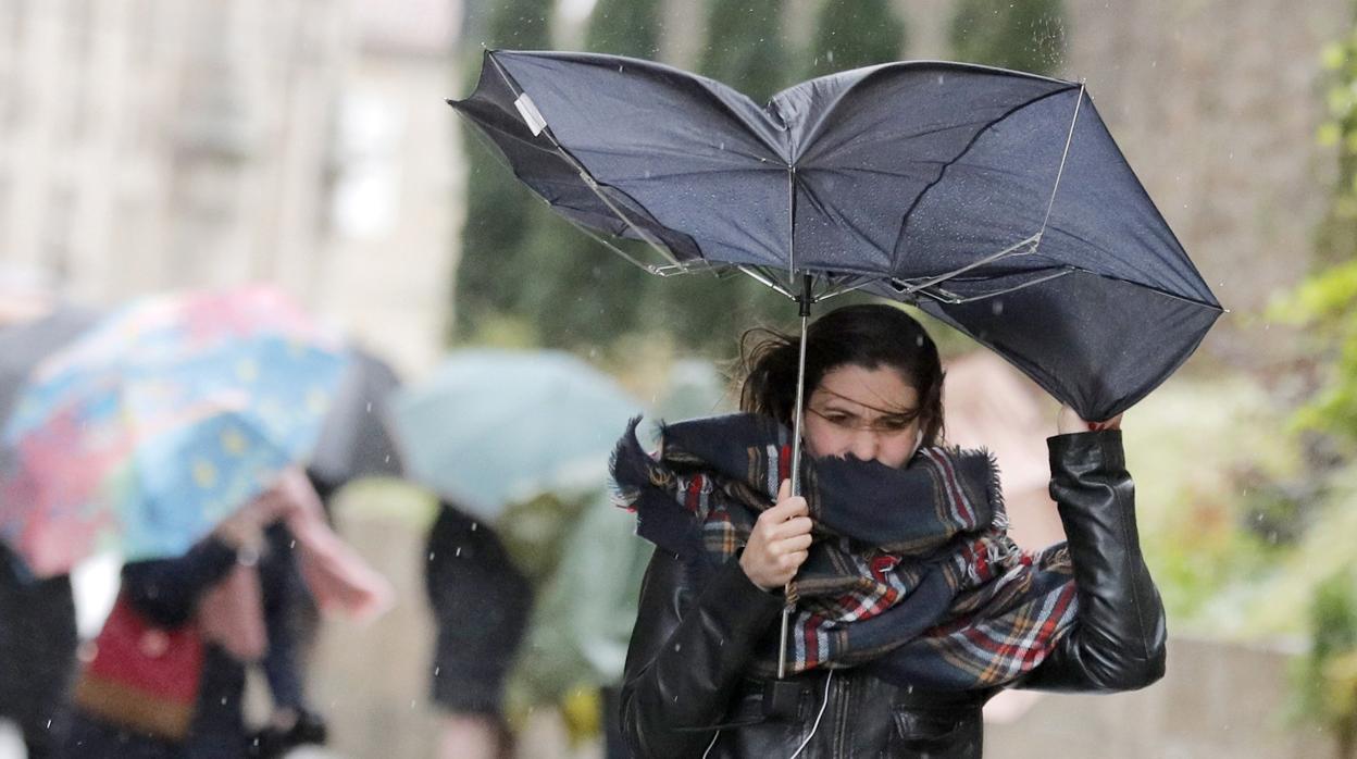 Una mujer combate los fuertes vientos y la lluvia