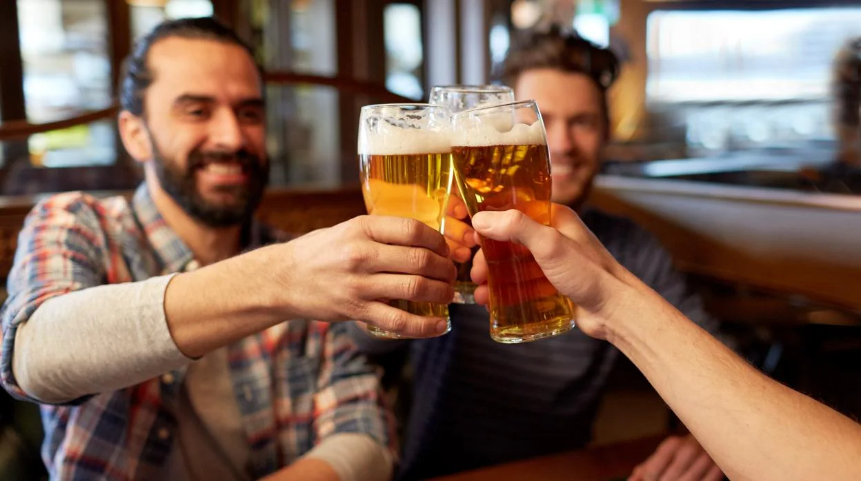 Un grupo de amigos consumen cerveza en un pub