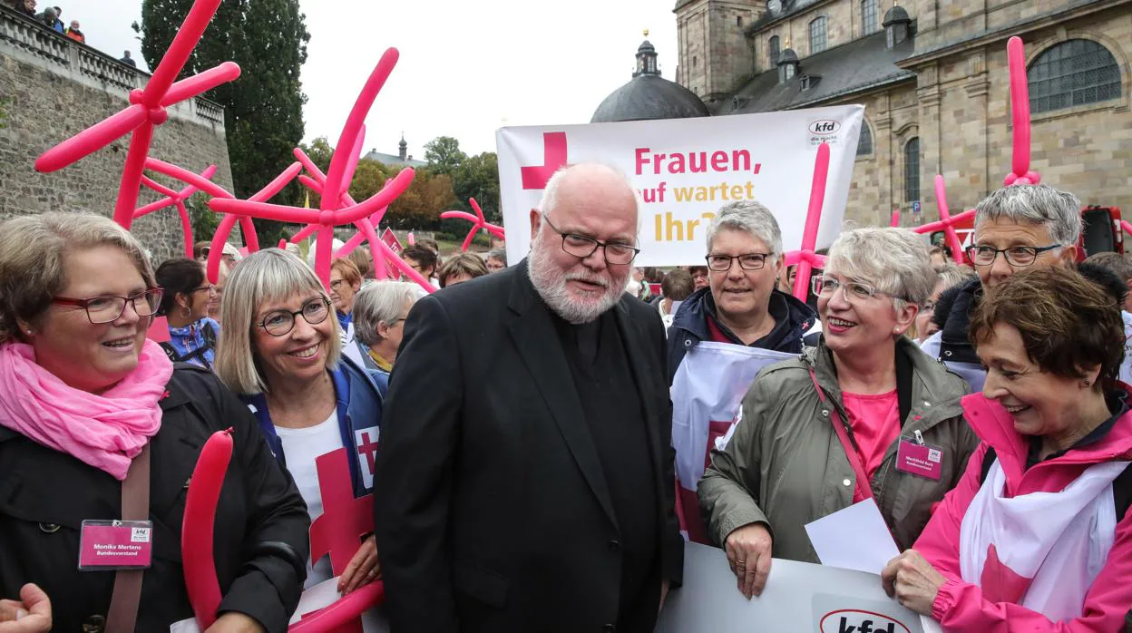 El presidente de la Conferencia Episcopal Alemana, cardenal Reinhard Marx (centro) habla con un grupo de mujeres que protestaban antes de la conferencia de prensa sobre la apertura de la sesión plenaria de Alemania