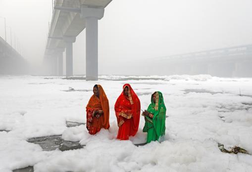 Las mujeres hindúes adoran al dios Sol en las aguas contaminadas del río Yamuna en Nueva Delhi