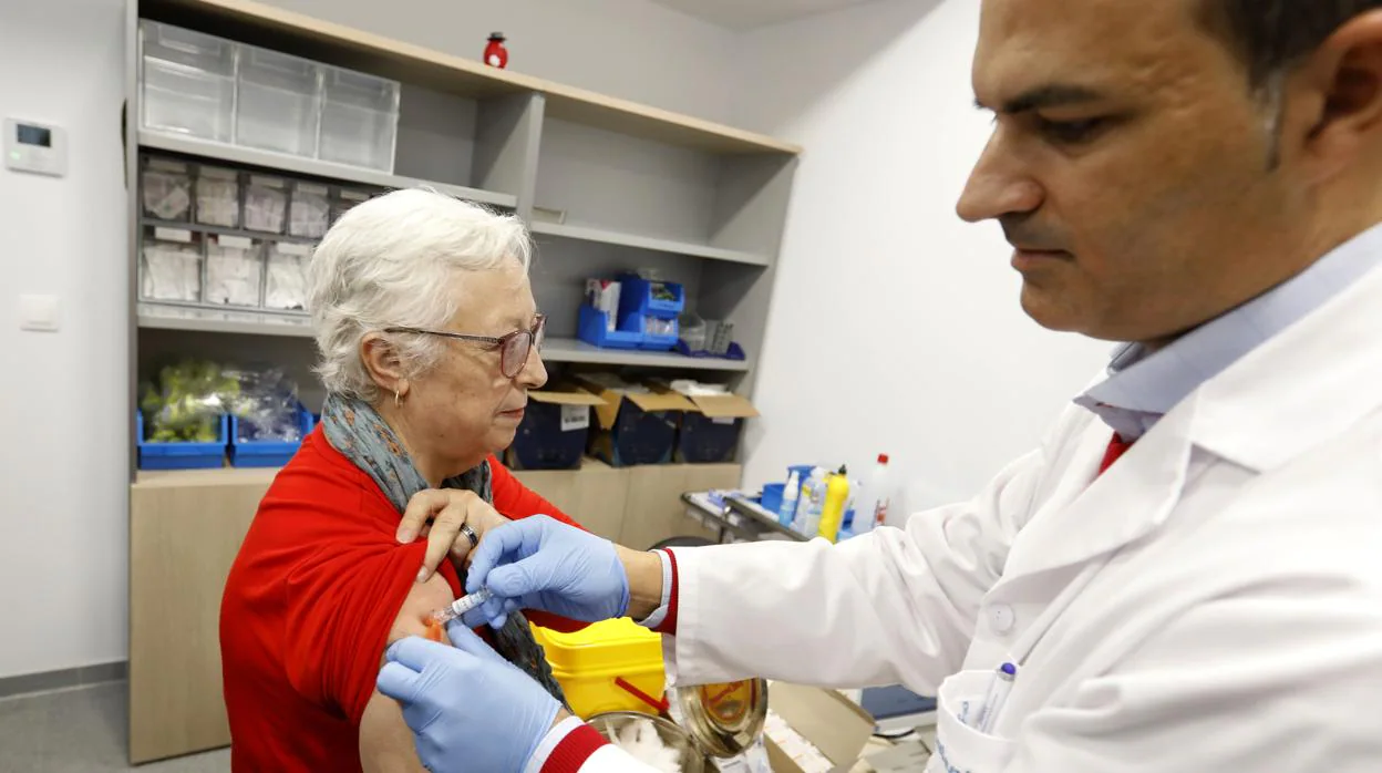 Un médico vacuna a una anciana contra la gripe