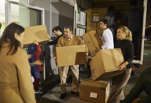 Varios voluntarios descargan las cajas que contienen el material de abrigo