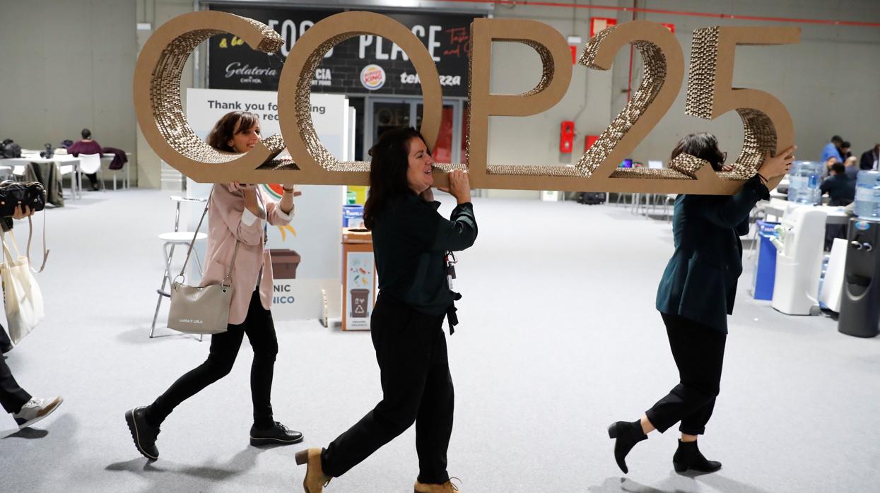 Tres mujeres retiran un logo de la Cumbre del Clima