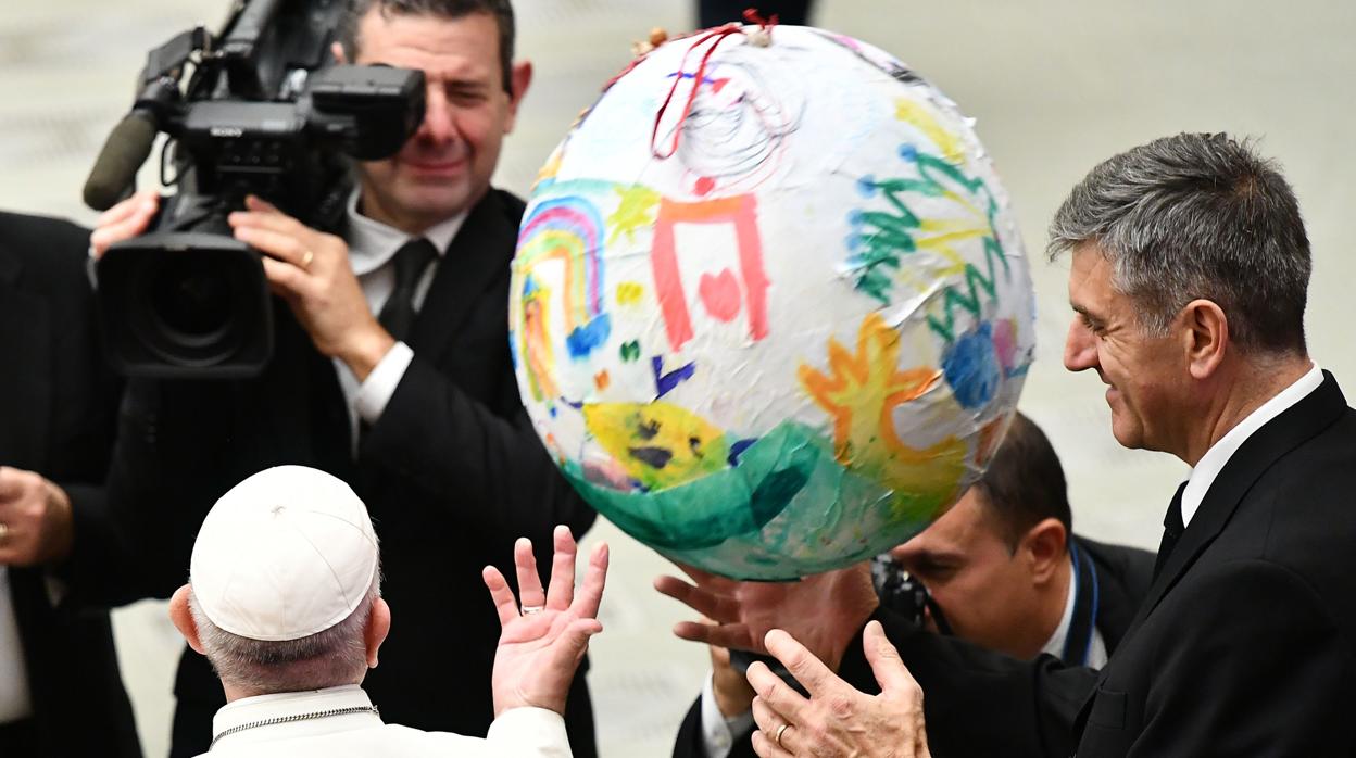 El Papa Francisco (L) y su mayordomo, Sandro Mariotti (R) rjuegan con una esfera cubierta de dibujos infantiles que el Papa recibió durante una ceremonia navideña con los empleados del Vaticano